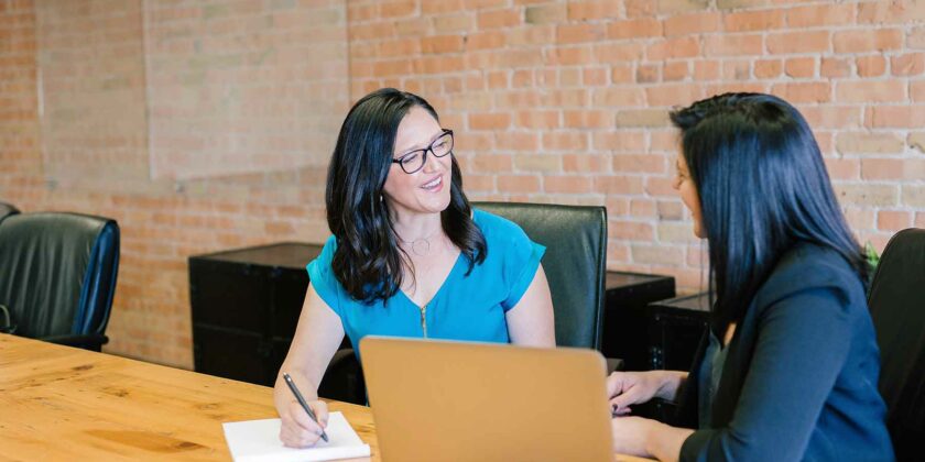 two women talking in front of a computer
