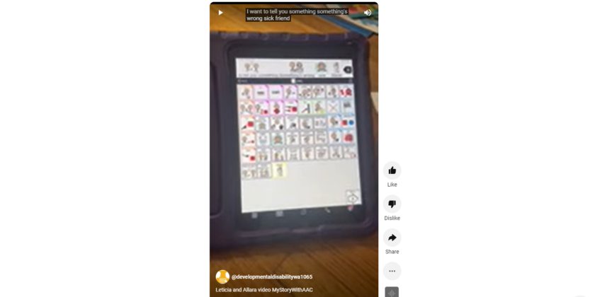 Image description: photo of a communication device page with a person's right hand pointing at the tile with image of "tell you something, something's wrong, sick, friend".