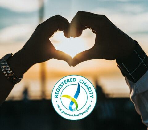 an image of two hands held together to form the outline of a love heart with a sun shining through the heart centre and the logo for "registered charity" beneath.