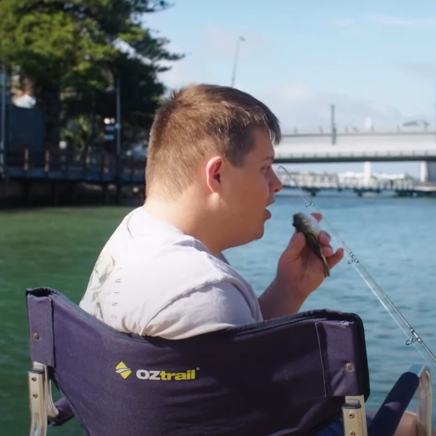 Down Syndrome person fishing and having caught something is holding it in hand