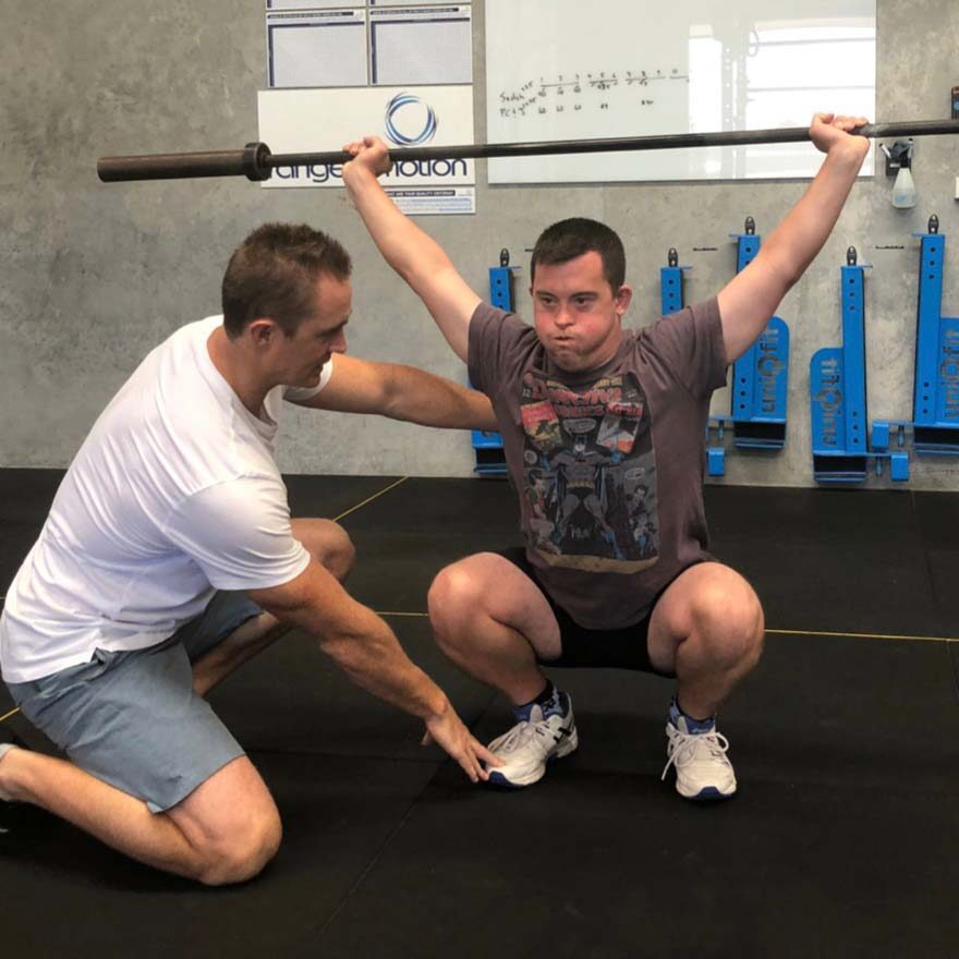 person at the gym holding a weight bar above their head