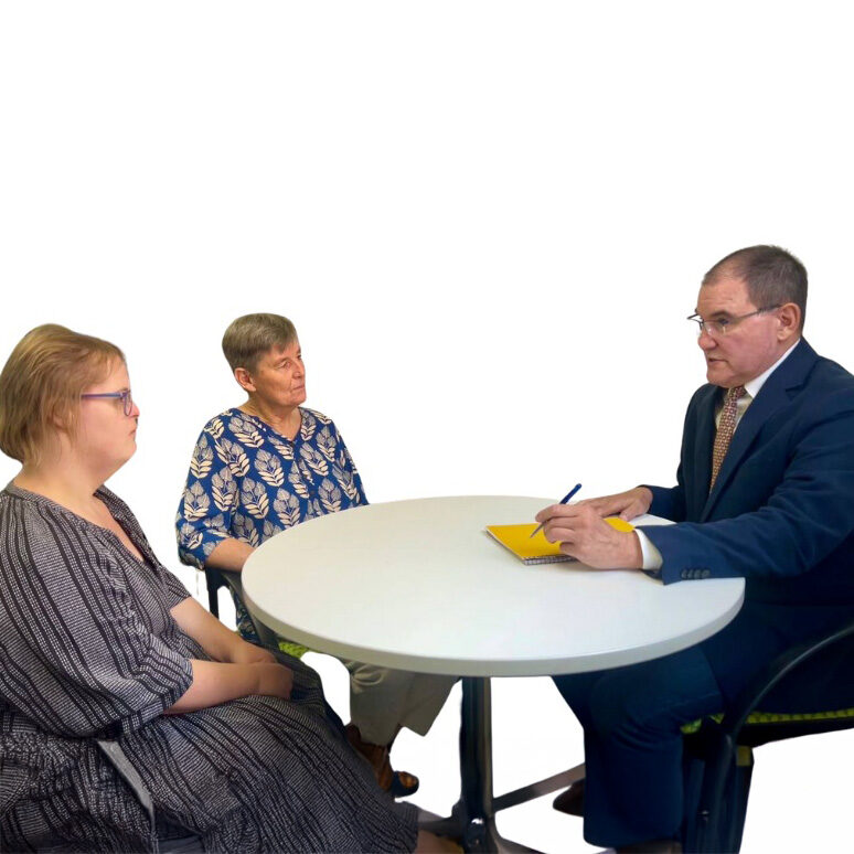 Person with disability and their advocate sitting at a table having a meeting with their lawyer.